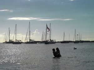 Bruidspaar in water op achtergrond boot met wimpel